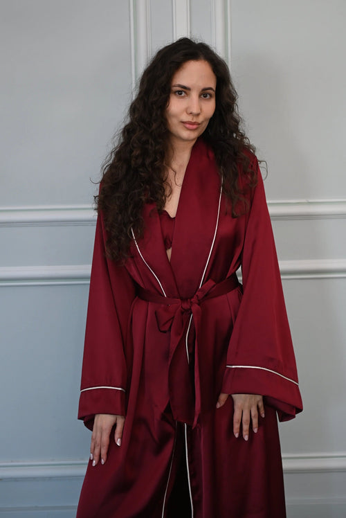 Woman wearing a burgundy robe against a light gray wall
